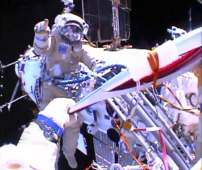 Russian astronaut Oleg Kotov holds an Olympic torch as he takes it on a spacewalk as Russian astronaut Sergei Ryazansky gives instructions outside the International Space Station